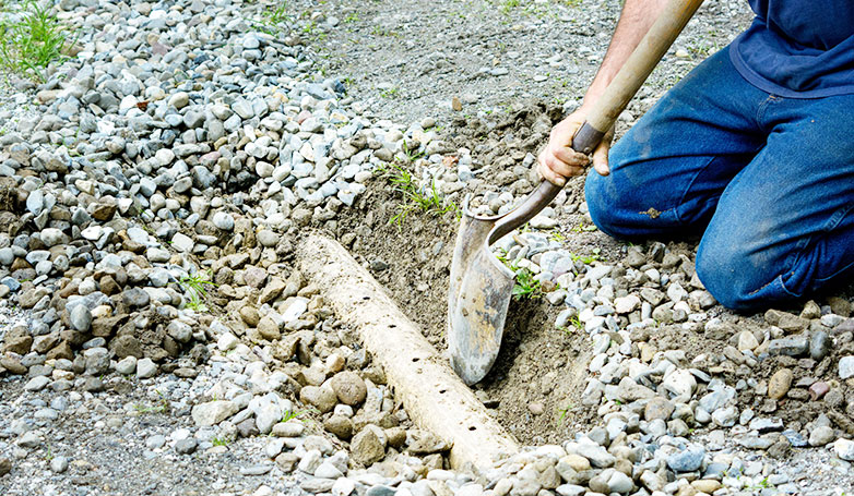 A worker busy for digging to clean a water drainage for driveway