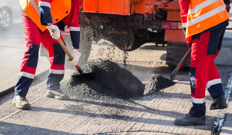 Workmen are repairing a pothole on a private driveway