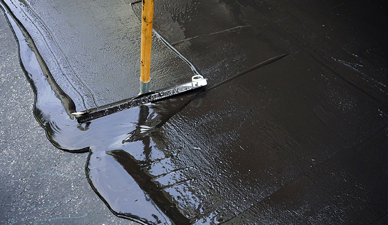 This image shows the process of seal coating of asphalt.