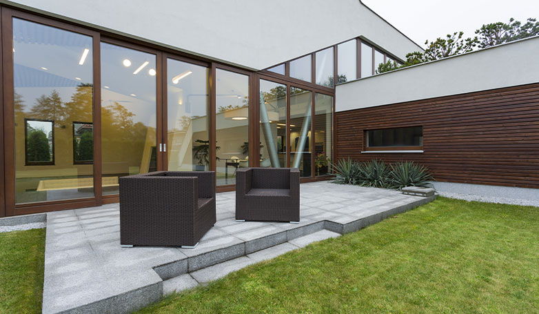 A modern patio can be found in the backyard of the house.