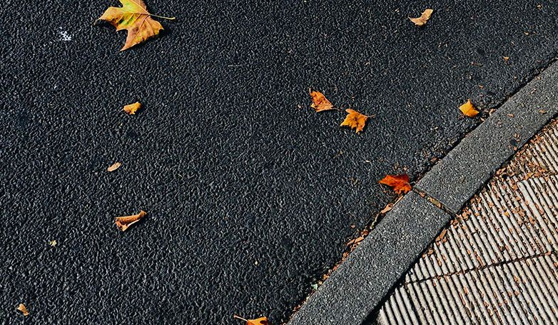 The newly installed asphalt driveway from recycled with leaves at in top.