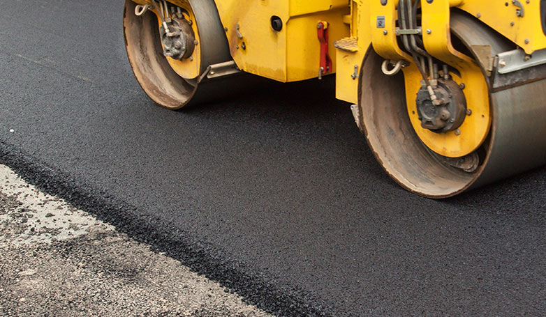 A worker flat the surface of new residential asphalt paving