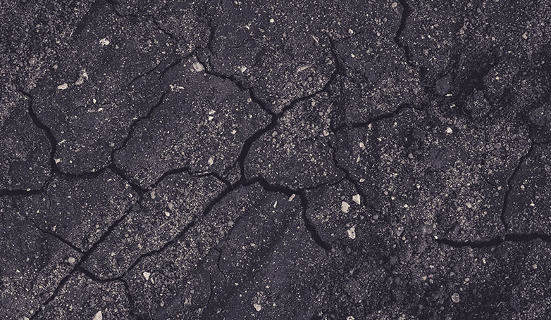 A damaged asphalt driveway with salt on the surface