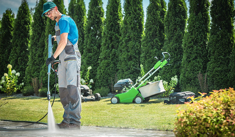 A man is using pressure washers to clean a sandstone paving.
