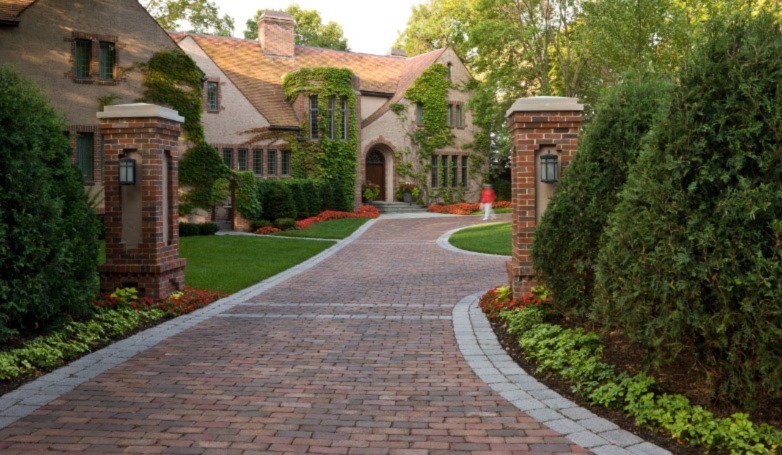 A house with a bricks driveway surrounded by greens