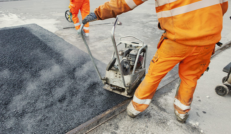 The workers busy on installing asphalt at the surface of the concrete road