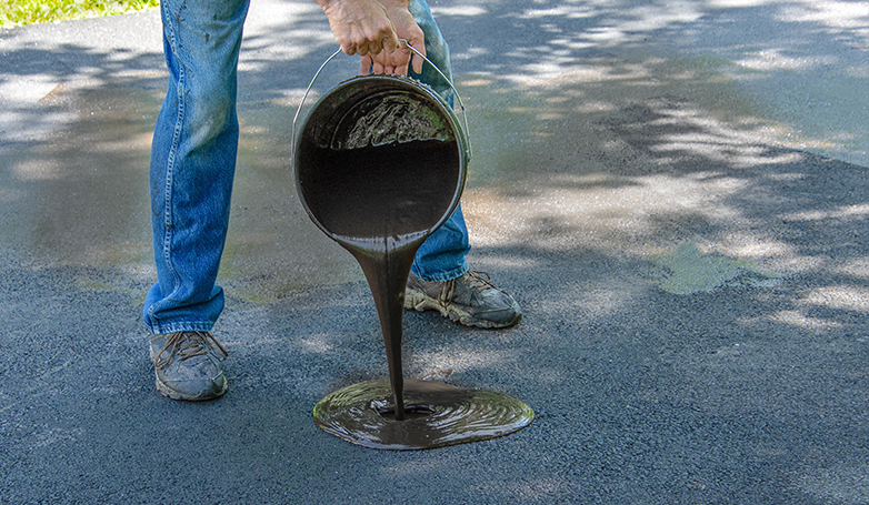 A man sealing a pothole on Asphalt driveway