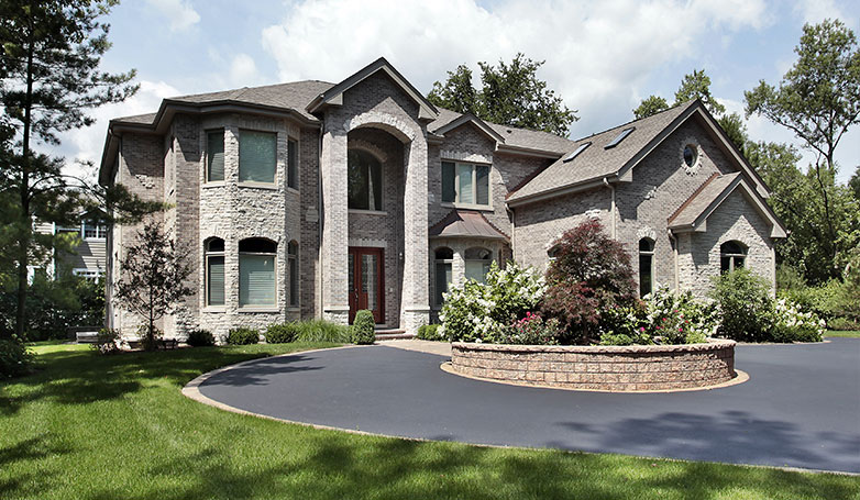 A big house with a residential blacktop driveway.