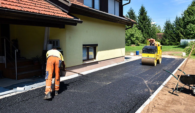 A workers busy on making a driveway using a blacktop.