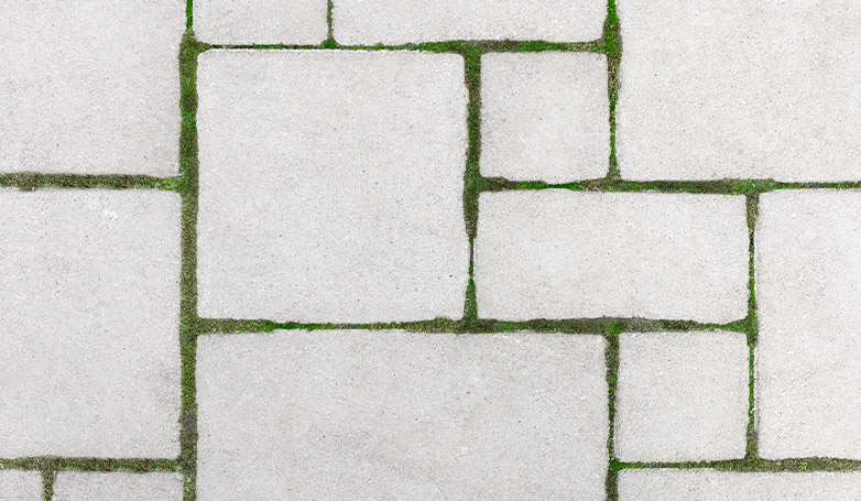 A concrete paving with grass underneath on it.