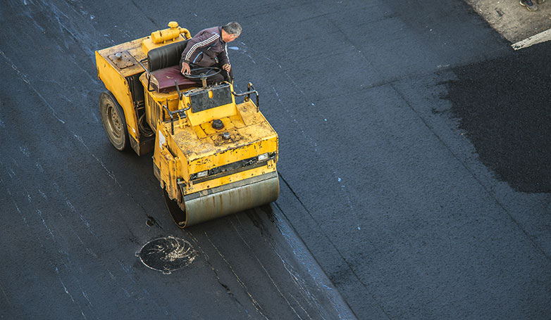 A worker leveling the newly installed asphalt roads.