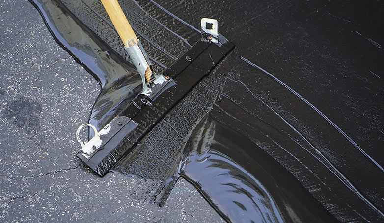 The process of seal coating on asphalt driveway