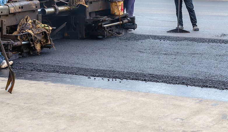 A busy workers installing a new asphalt pavement on road