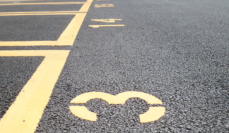 A tar and chip parking lot with yellow paint numbers guide.