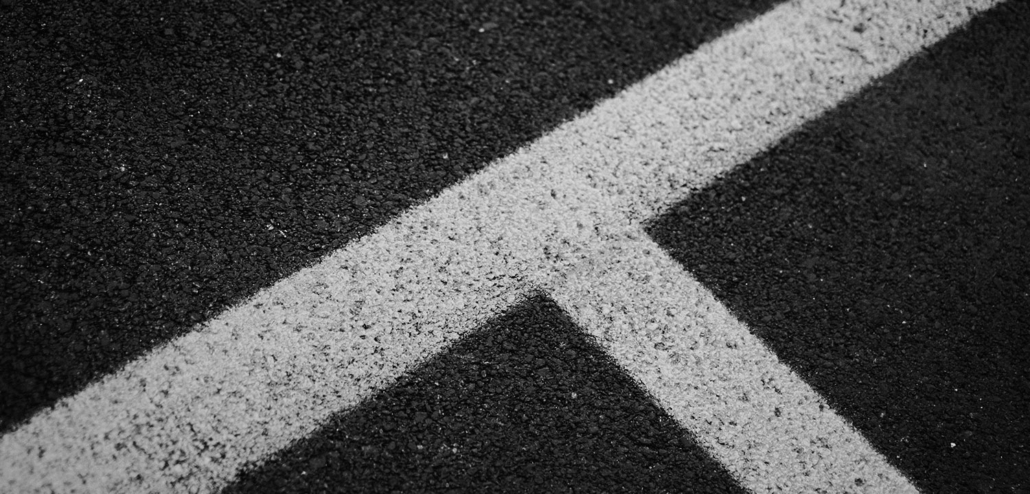 A white parking lot line guide over Tar and Chip.