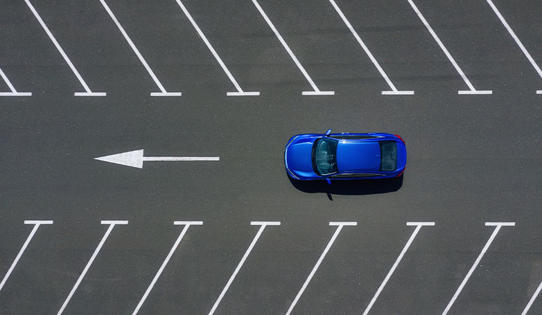 A blue car driving on new asphalt parking lot