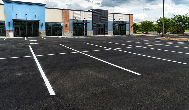 An asphalt parking lot in front of restaurants.