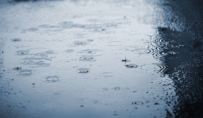 A rain drops on asphalt driveway with seal coating.