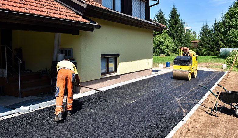 A workers busy on resurfacing an asphalt driveway.