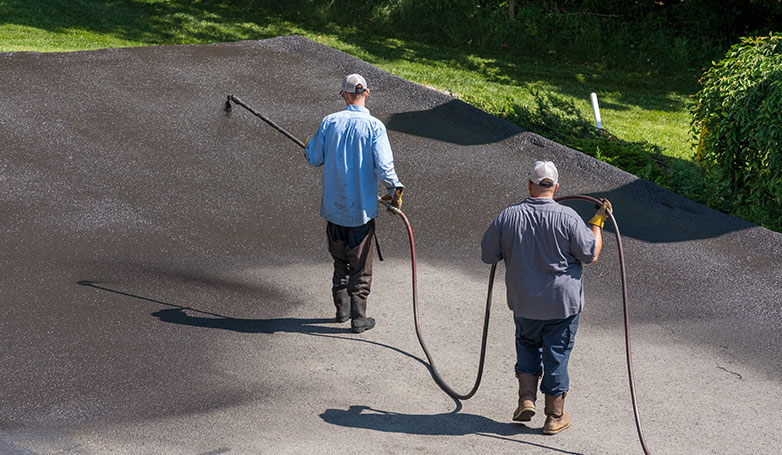 Workers are busy applying a seal coat on the concrete driveway.