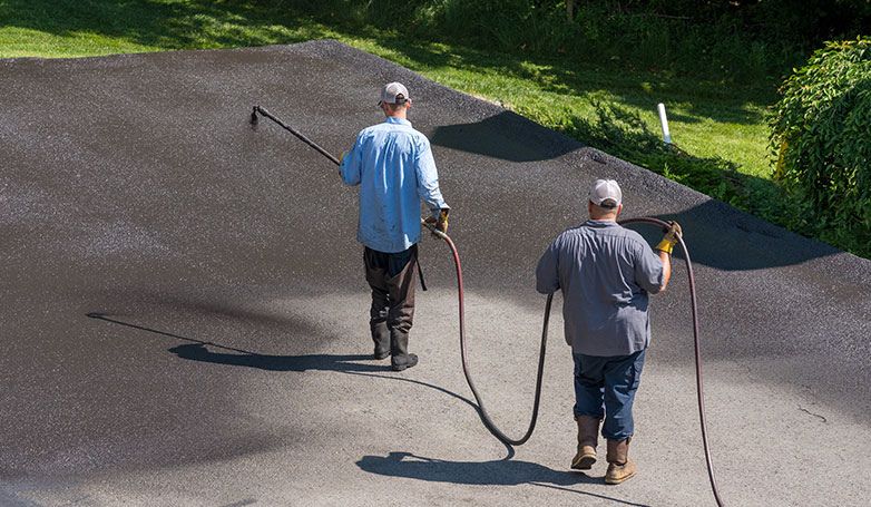 A workers busy on sealcoating the driveway.