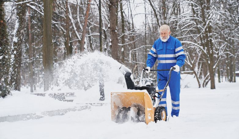 the worker is using a functional machine to plow the driveway of snow