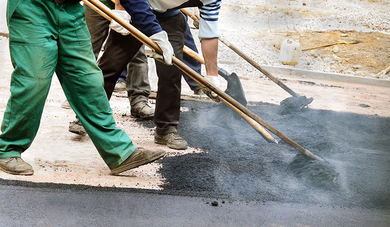 Workers are repairing the driveway with recycled asphalt