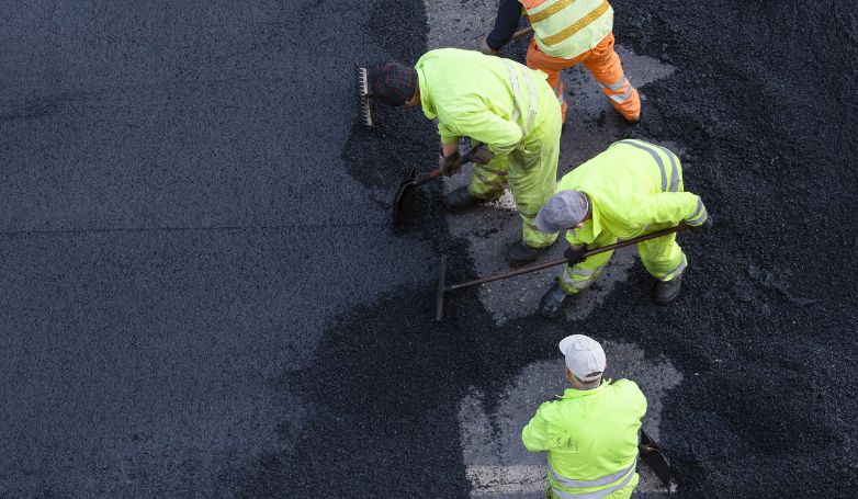 Workers are installing the asphalt after calculating its environmental impact