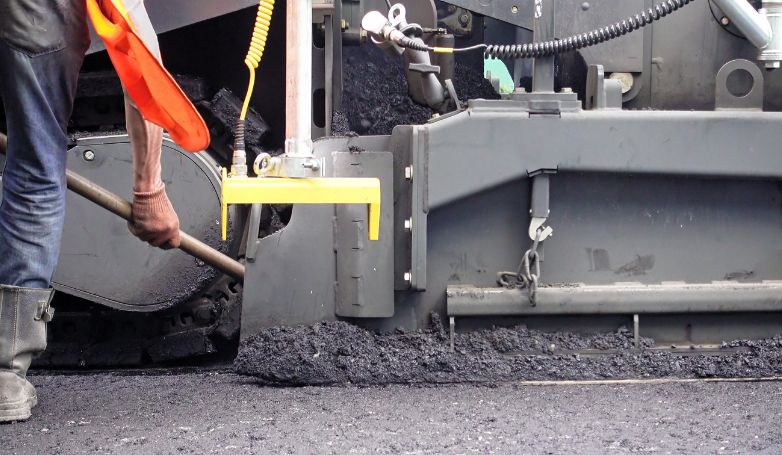 The worker is installing recycled asphalt on the driveway