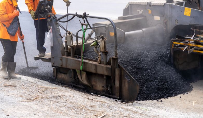 The machine is laying fresh asphalt to pave the road.