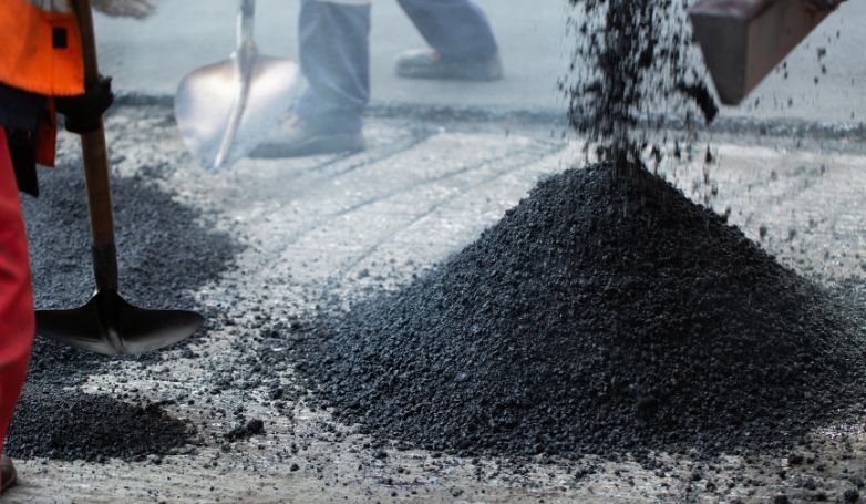 The workers are using asphalt to pave a road.