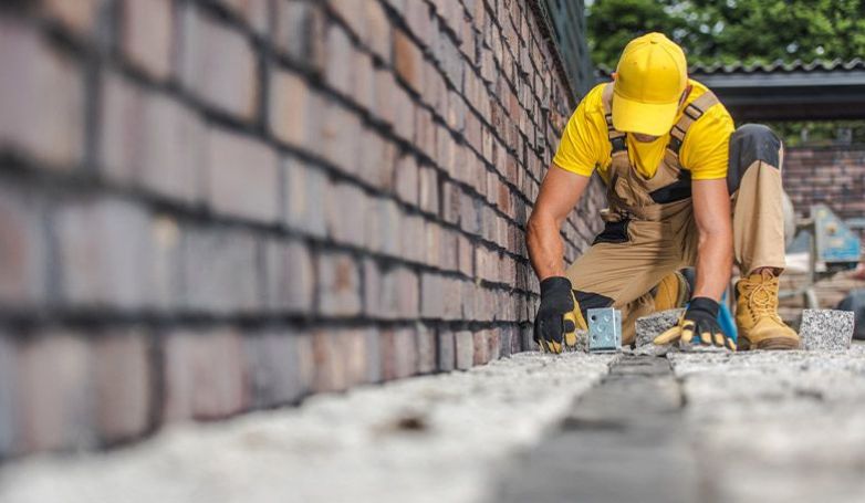 A worker replacing the damaged brick on the driveway