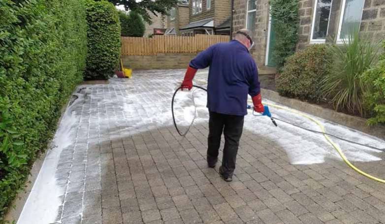 The worker cleans the newly installed brick driveway.