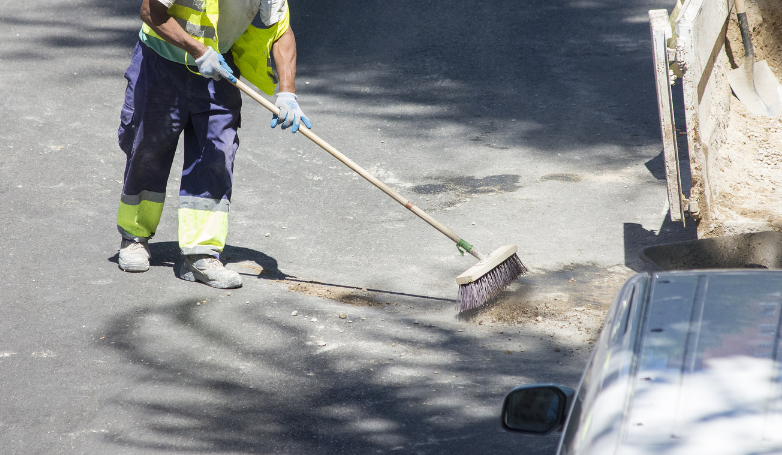 The worker is showing how to clean the tarmac driveway
