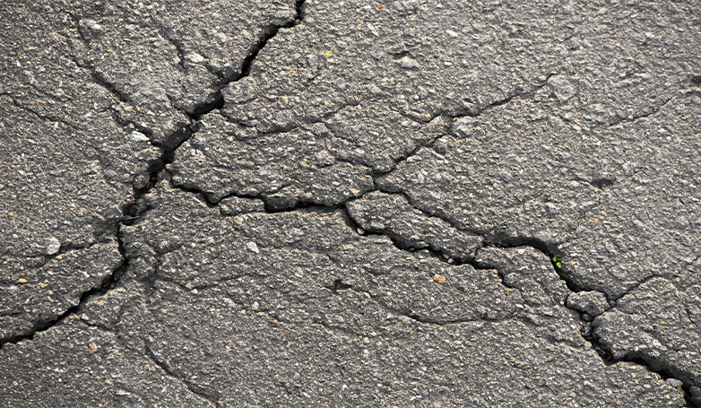 Some cracks have appeared in the asphalt of the parking lot